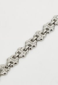 Svensk metallarmband i silver med hopkopplade länkar med en slät, glänsande yta; länkarna liknar ett geometriskt mönster.