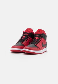 Een paar rood-zwart hoge Air Jordan sneakers met zwarte veters, witte tussenzolen en het Jumpman-logo op de tongen en zijkanten.