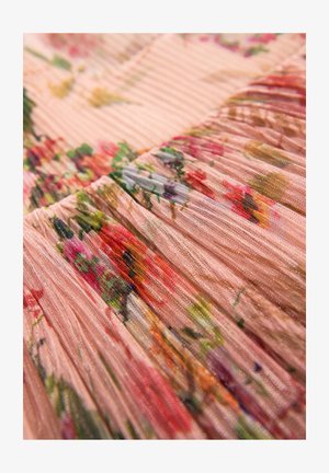 Plissé látka v jemné růžové barvě s květinovými vzory obsahujícími odstíny červené, zelené a žluté. Textura působí lehce a vzdušně.