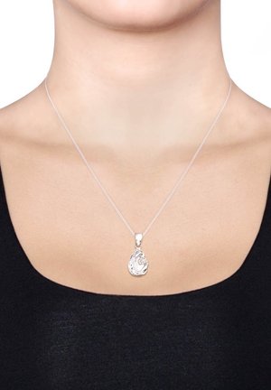 Silberne Halskette mit einem tropfenförmigen Anhänger, der über eine strukturierte Oberfläche verfügt. Dünne Kette, die vor einem schwarzen Oberteil sichtbar ist.