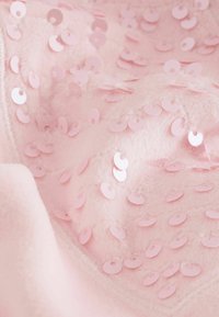 Rosa Stoff mit zahlreichen glänzenden, flachen Pailletten in verschiedenen Größen, die über die Oberfläche verteilt sind und einen strukturierten, schimmernden Effekt erzeugen.