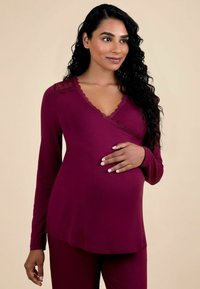 Haut de maternité bordeaux à manches longues, avec des accents en dentelle au niveau du col, et un design enroulé, assorti à un bas en tissu lisse.