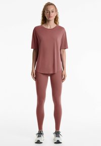 Completo sportivo in un rosa tenue. Il top a maniche corte presenta un orlo arrotondato; i leggings hanno pannelli testurizzati e una vita alta.