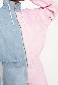 Džínová bunda s designem půl na půl - světle modrá a růžová, s vysokým límcem, zipem na zapínání a elastickým pasem pro lepší přizpůsobení.