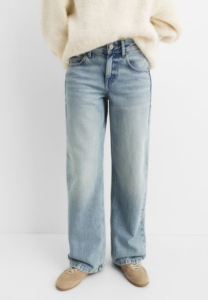Light blue wide-leg jeans worn with beige sneakers and a cream-colored fuzzy sweater, shown from waist to feet on a white background.
