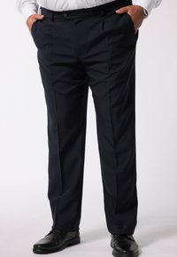 Marinefarbene Anzughosen aus glattem Stoff, mit lockerem Schnitt, Falten und Seitentaschen, kombiniert mit glänzenden schwarzen Anzugschuhen.