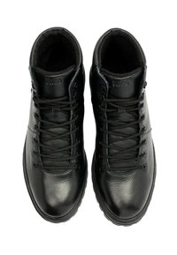 Czarne skórzane buty o gładkiej fakturze, okrągłym czubku i kontrastowych sznurówkach. Posiadają logo na kołnierzu oraz wysokie wsparcie kostki dla stabilności.