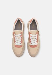 Zapatillas ligeras con un diseño en beige y rosa, con un empeine de lona texturizada, cordones blancos y un detalle de cremallera dorada.