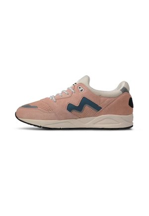 Zapatilla de ante rosa con cordones blancos, suela beige, suela exterior negra y logotipo azul marino ondulado en el costado, mostrada en perfil lateral.