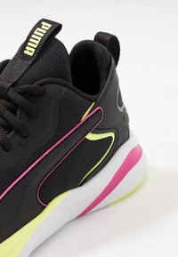 Černé tenisky s síťovaným svrškem, neonově žlutými a růžovými akcenty, silnou bílou podrážkou a texturovanými panely. Obsahují poutko a šněrování.