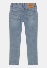 Jeans de mezclilla de color azul claro con pierna recta, un ligero desgaste, dos bolsillos traseros y una etiqueta de cuero marrón en la cintura.