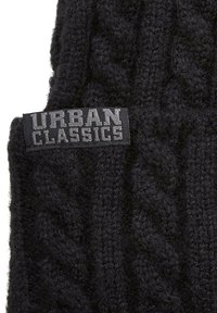 Berretto di lana nera con un motivo a treccia testurizzato. Presenta un'etichetta rettangolare cucita con la scritta "URBAN CLASSICS" in grigio.