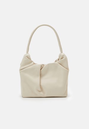 Weiche beige Handtasche mit gerafftem, gerafftem Design und einem einzelnen runden oberen Griff vor einem einfarbigen weißen Hintergrund.