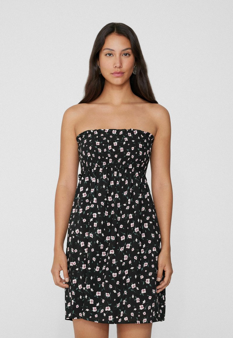 Schulterfreies schwarzes Kleid mit floralen Mustern, elastischem Mieder und lockerem Rock. Leichter Stoff mit kleinen rosa und grünen Akzenten.