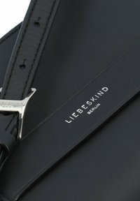 Schwarze Leder-Crossbody-Tasche mit einem schlanken Design, silberner Hardware und geprägtem Logo-Detailing auf dem vorderen Riemen.