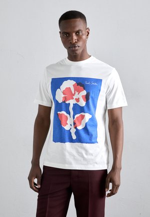 Witte katoenen t-shirt met een grote grafische print in blauw, rood en wit, waarop een bloemmotief met abstracte vormen is afgebeeld.