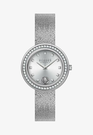 Silver analog watch with a textured band, round case, crystal accents, and a patterned dial featuring square markers and a logo at the bottom.