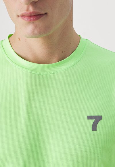 Neon grøn kortærmet skjorte med rund hals og struktureret stof; inkluderer et gråt nummer "7" på venstre brystområde.