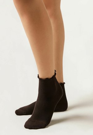 Schwarze Knöchelsocken mit gerippter Textur und gewelltem Saum am Bündchen, die ein enges Design zeigen.