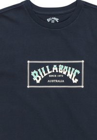 Navy blauwe katoenen t-shirt met een gecentreerd grafisch logo in wit en licht teal, met de tekst "BILLABONG SINCE 1973 AUSTRALIA" binnen een rand.