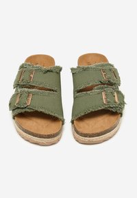 Green fabric slide sandals featuring frayed edges, two buckled straps, and a cork sole combined with jute accents.