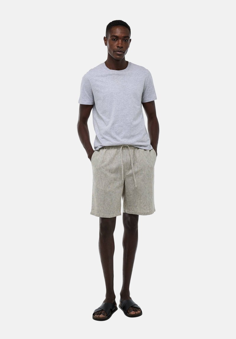 T-shirt gris à col rond, shorts rayés beige clair avec cordon de serrage, et sandales noires. Design simple avec une coupe décontractée et un tissu doux.