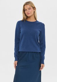 Navyblauwe gebreide trui met lange mouwen en een ronde halslijn, gecombineerd met een bijpassende navyblauwe rok, voor een samenhangende uitstraling.