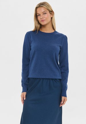 Pulover tricotat de culoare bleumarin cu mâneci lungi și decolteu rotund, asortat cu o fustă bleumarin, creând un aspect unitar.