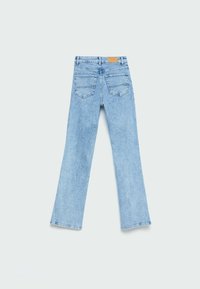 Jean en denim bleu clair évasé avec une taille mi-haute, deux poches arrière et un patch en cuir marron clair à la ceinture.
