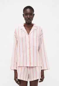 Randig pyjamas-set i ljusrosa med korallfärgade ränder; har en kn�äppskjorta med en ficka och matchande shorts, tillverkad av ett lätt material.