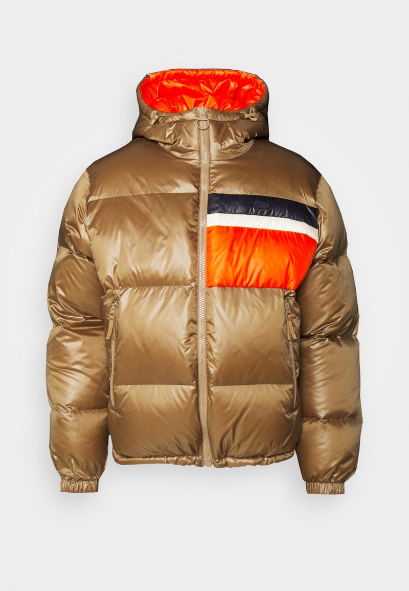 Braune Puffjacke mit Kapuze, Frontreißverschluss, Seitentaschen und einem Brustpatch, der aus schwarzen, weißen und leuchtend orangefarbenen Farbblöcken besteht.