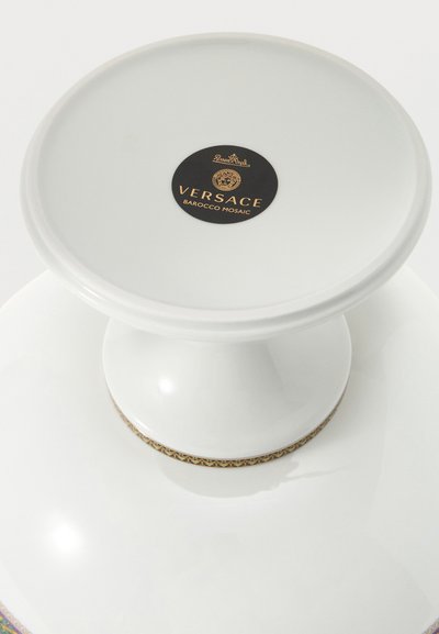 Λευκή κεραμική βάση τούρτας με χρυσή και μαύρη ετικέτα Versace Barocco Mosaic στην κορυφή και διακοσμητικό χρυσό περίγραμμα στη βάση.