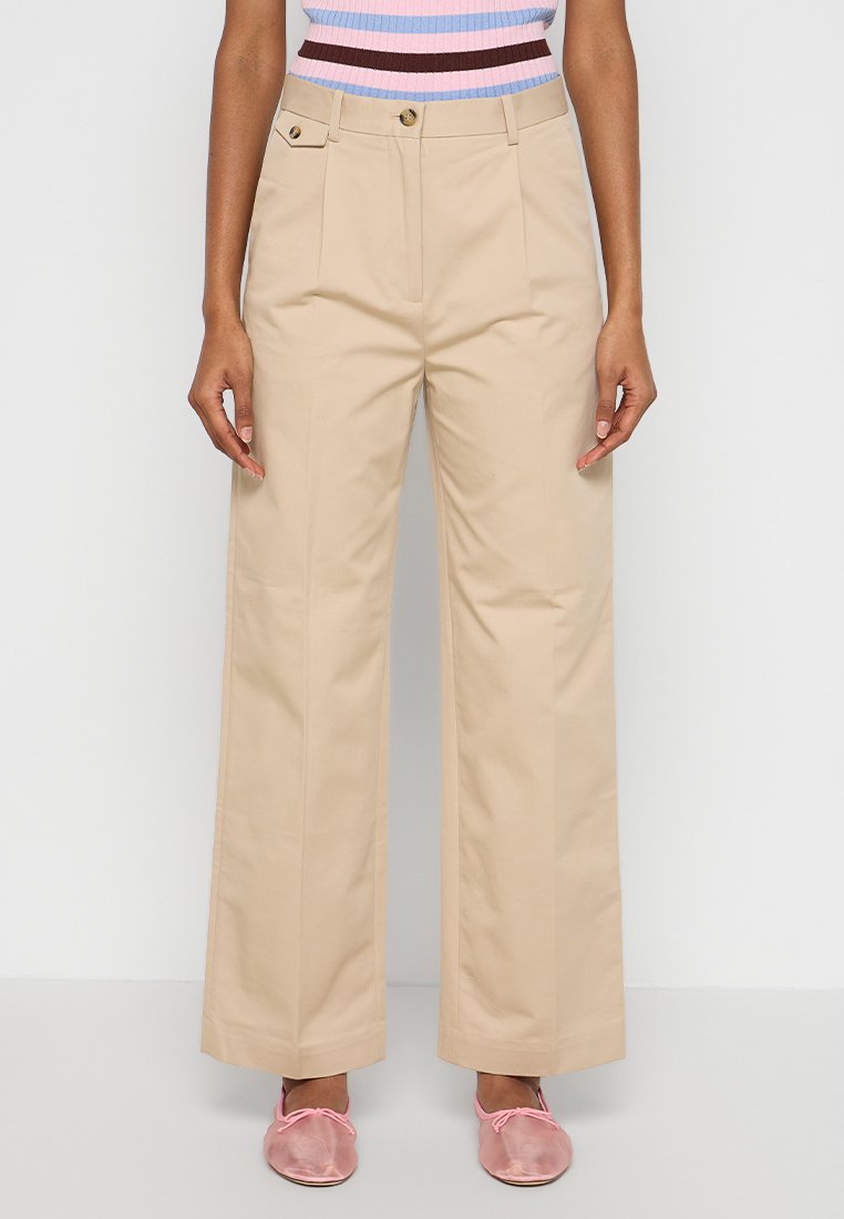 Pantaloni beige a palazzo con pieghe frontali, due tasche laterali e bottoni dorati in vita. Il tessuto sembra liscio e strutturato.