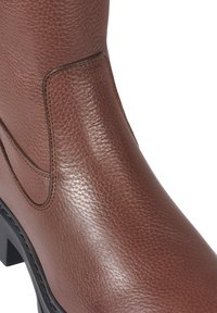 Brune lær ankle boot med teksturert finish, elastiske sidepaneler og en kraftig svart såle. Stitchingdetaljer gir subtile aksenter.