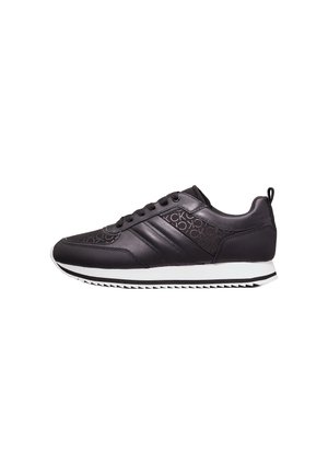 Zapatillas deportivas negras de cuero liso, con tres franjas en el costado, un upper texturizado y suela de goma blanca con un patrón en zigzag.