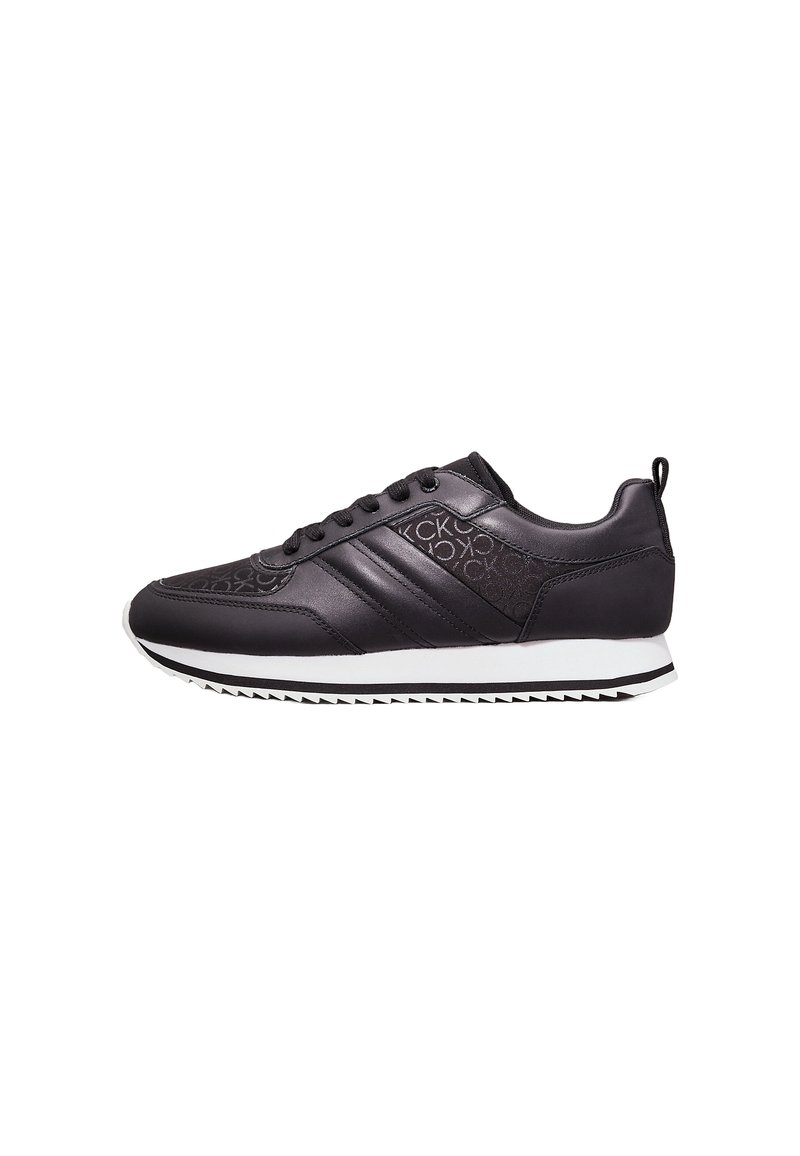 Zapatillas deportivas negras de cuero liso, con tres franjas en el costado, un upper texturizado y suela de goma blanca con un patrón en zigzag.
