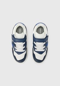 Modré a biele tenisky s koženým a sieťovinovým zvrškom, suchým zipsom a gumovou podrážkou; obsahujú perforované detaily pre lepšiu priedušnosť.