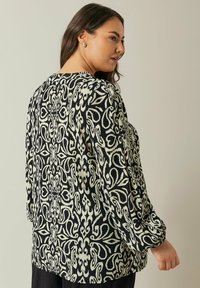 Sort og cremefarvet bluse med mønster, lange ærmer og elastiske manchetter, med et blomsterdesign og en afslappet pasform. Blødt, letvægtsstof.
