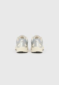 Des chaussures de sport argent et crème avec une tige en mesh texturé, une forme arrondie, une semelle rembourrée et un logo Nike distinctif.
