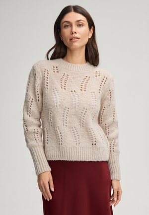Lichtbeige gebreide trui met open steekpatronen en geribbelde manchetten. Zachte textuur, ronde halslijn en cropped ontwerp.