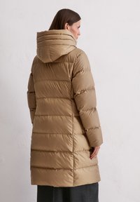 Beidzēti pelēkā puffer apmetnis ar kapuci, nodrošināts ar quilted rakstu un vidēju garumu, pabeigts ar gludu, spīdīgu tekstūru.