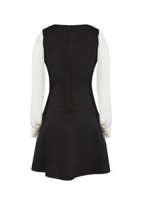 Robe noire sans manches avec manches longues blanches plissées attachées et poignets boutonnés, vue de dos sur fond blanc.