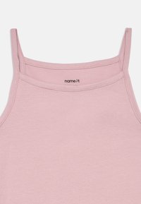 Ανοιχτό ροζ αμάνικο μπλουζάκι με λεπτές τιράντες, φτιαγμένο από μαλακό βαμβακερό ύφασμα. Διαθέτει στρογγυλή λαιμόκοψη και ετικέτα με την ένδειξη "name it" μέσα.