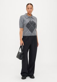 Gray short-sleeve knit sweater with a diamond pattern, paired with black wide-leg trousers and a black handbag with studded straps.