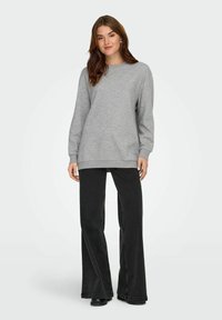 Sudadera gris de manga larga y cuello redondo, combinada con jeans negros de pierna acampanada. Textura suave, diseño casual, sin patrones visibles.