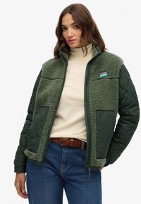 Groene fleece-gevoerde jas met gewatteerde mouwen en voorkant zakken, voorzien van een rits, hoge kraag en een merkpatch op de borst.