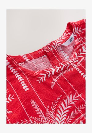 Raudonas medvilninis viršus su apvalia iškirpte, baltais papartų raštais ir tekstūruota medžiaga. Etiketėje šalia iškirptės matyti užrašas „NEXT“.