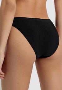 Black swimsuit bottoms with a high-cut design. Made of smooth, stretchy fabric, featuring clean lines and minimal stitching.
