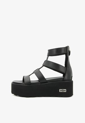 Sandali neri con piattaforma, caratterizzati da più cinturini, design aperto sulla punta e suola texture. Presentano una chiusura con zip sul retro e un logo del marchio.