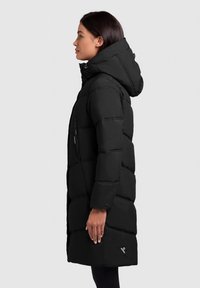 Schwarze Pufferjacke mit Kapuze, mit gestepptem Design, Reißverschlusstaschen und einem Logo-Detail am Saum. Glatte, matte Textur.